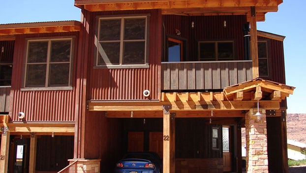 A front view of townhouse Unit #22 at Moab Spring Ranch with a two space garage with a bright blue car parked beneath.