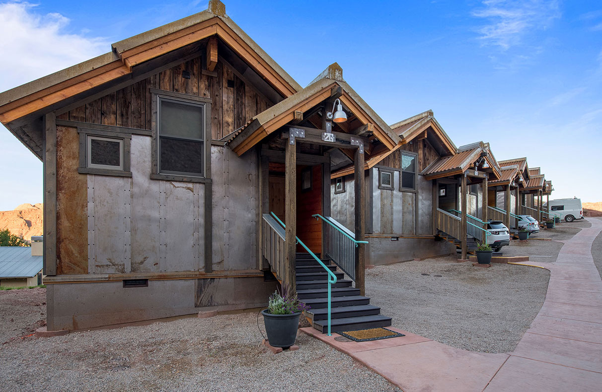 A view of the two-car garage spaces of Units #17 and 18 at Moab Springs Ranch, with brick and wood columns, ceiling lighting and cement car stops.